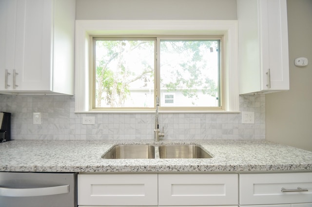 kitchen with white cabinetry, sink, backsplash, and light stone counters