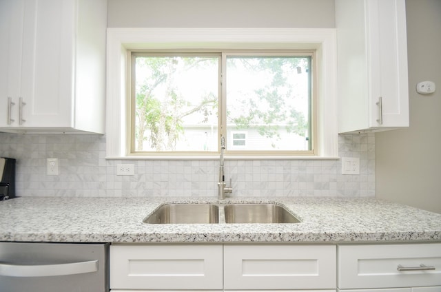 kitchen featuring white cabinetry, sink, decorative backsplash, stainless steel dishwasher, and light stone countertops