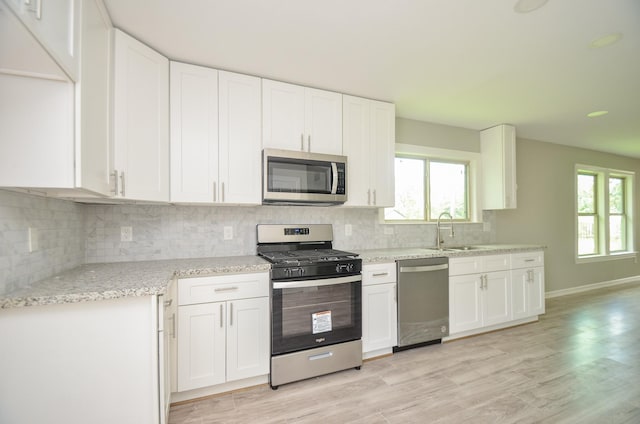 kitchen with appliances with stainless steel finishes, sink, and white cabinets