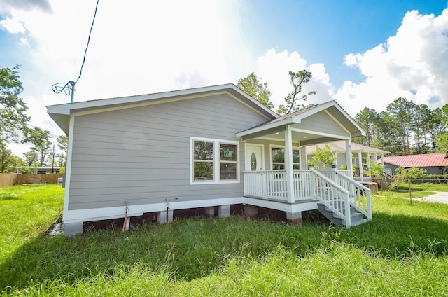 back of house featuring a lawn and covered porch