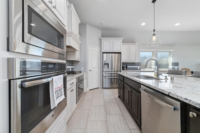 kitchen featuring sink, white cabinetry, stainless steel appliances, tasteful backsplash, and decorative light fixtures