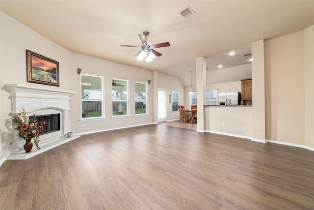 unfurnished living room featuring lofted ceiling, hardwood / wood-style flooring, a high end fireplace, and ceiling fan