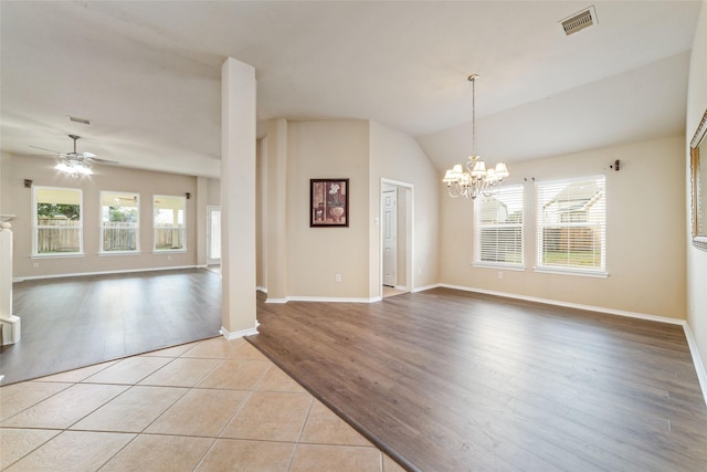 spare room with ceiling fan with notable chandelier, light tile patterned floors, and lofted ceiling