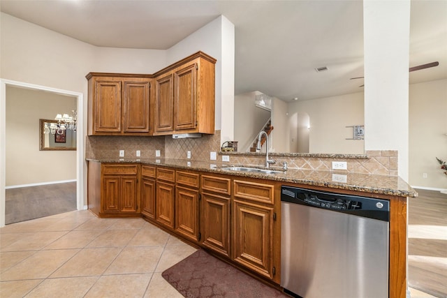 kitchen with sink, tasteful backsplash, kitchen peninsula, dishwasher, and light stone countertops