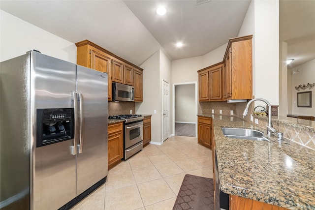 kitchen with stone counters, appliances with stainless steel finishes, sink, decorative backsplash, and light tile patterned floors