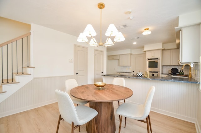 dining room featuring a notable chandelier, light hardwood / wood-style floors, and sink