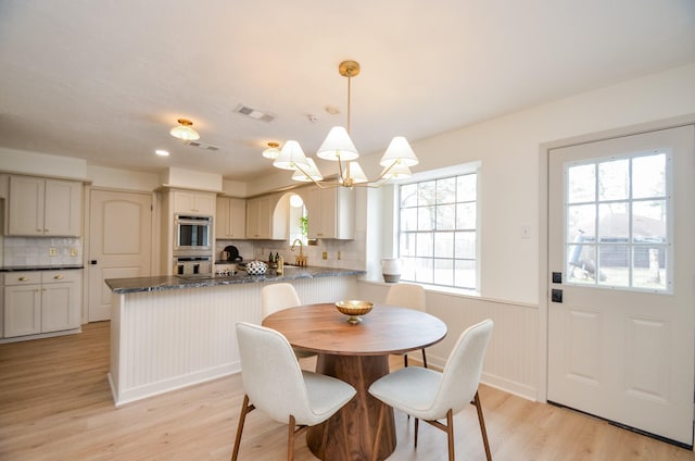 dining space with sink, an inviting chandelier, and light hardwood / wood-style flooring