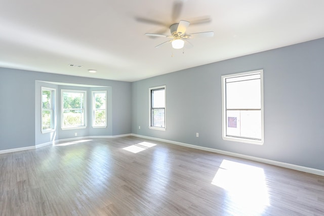 empty room with ceiling fan and light hardwood / wood-style flooring