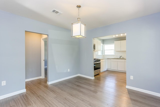 unfurnished dining area with sink and light hardwood / wood-style flooring