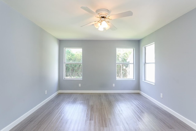 spare room featuring dark wood-type flooring, a wealth of natural light, and ceiling fan