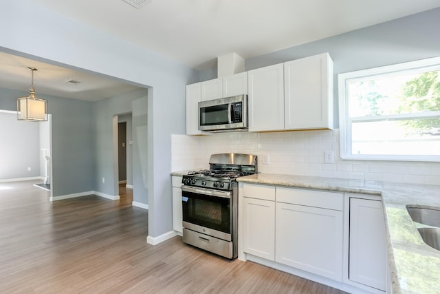 kitchen with white cabinetry, tasteful backsplash, appliances with stainless steel finishes, and light stone counters