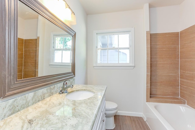 bathroom with a washtub, vanity, hardwood / wood-style floors, and toilet