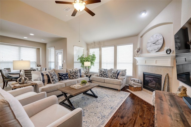 living room featuring ceiling fan, dark hardwood / wood-style flooring, vaulted ceiling, and a tile fireplace