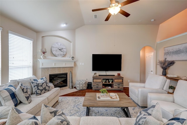 living room with lofted ceiling, a tiled fireplace, ceiling fan, and hardwood / wood-style flooring