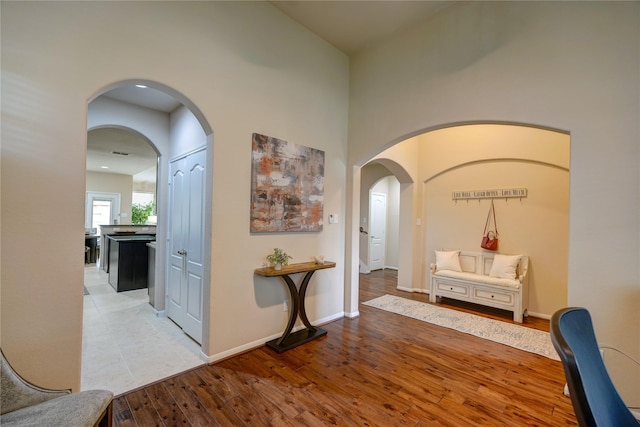 hallway with a towering ceiling and light hardwood / wood-style flooring