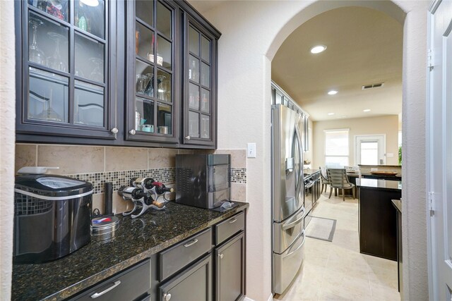 kitchen with decorative backsplash, dark stone counters, and stainless steel fridge with ice dispenser