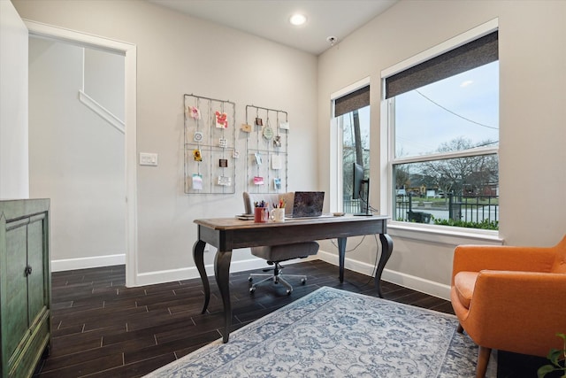 office space featuring a wealth of natural light, dark wood-type flooring, and a water view