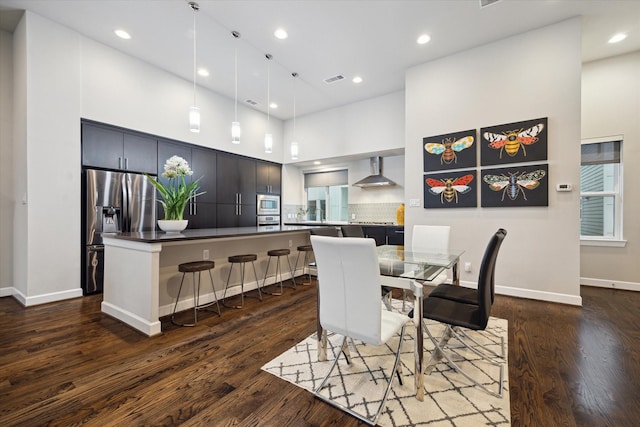 dining space featuring dark wood-type flooring and a towering ceiling