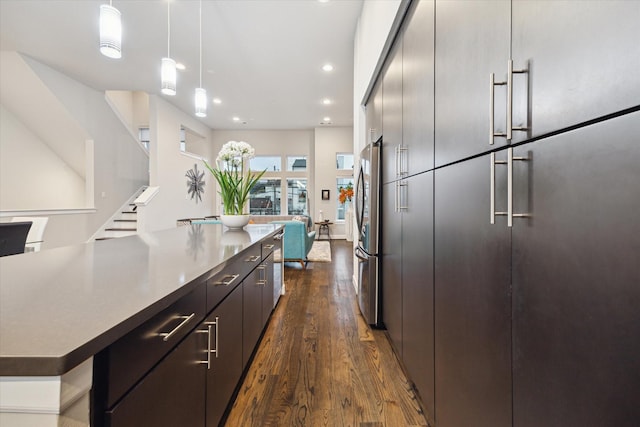 kitchen with stainless steel refrigerator, dark hardwood / wood-style flooring, a center island, and hanging light fixtures