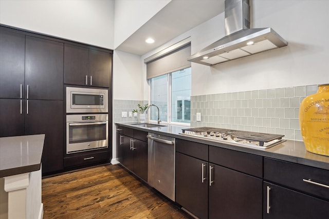 kitchen with sink, appliances with stainless steel finishes, dark brown cabinets, dark hardwood / wood-style flooring, and wall chimney exhaust hood