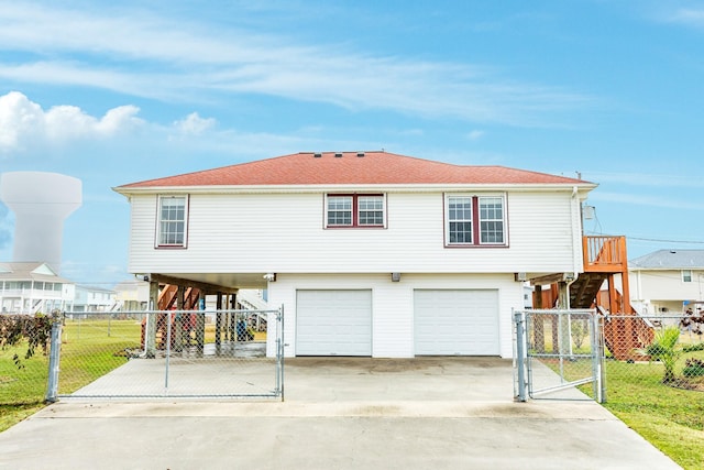 view of front of property featuring a garage, fence, stairs, driveway, and a gate