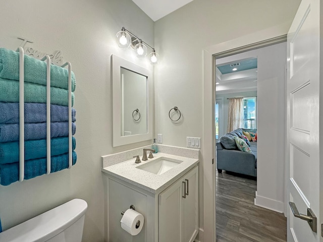 bathroom featuring hardwood / wood-style flooring, vanity, a raised ceiling, and toilet