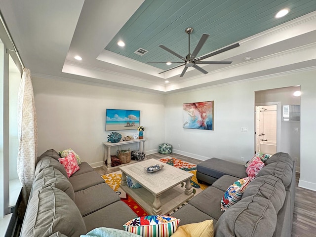 living room featuring a tray ceiling, wood-type flooring, ornamental molding, and ceiling fan