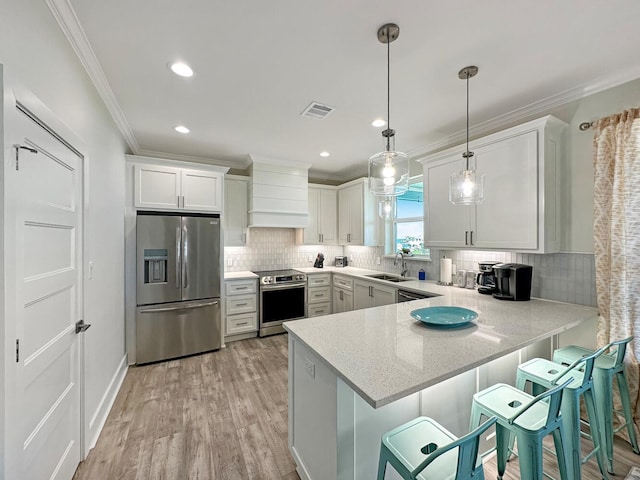 kitchen with a breakfast bar, hanging light fixtures, stainless steel appliances, white cabinets, and kitchen peninsula