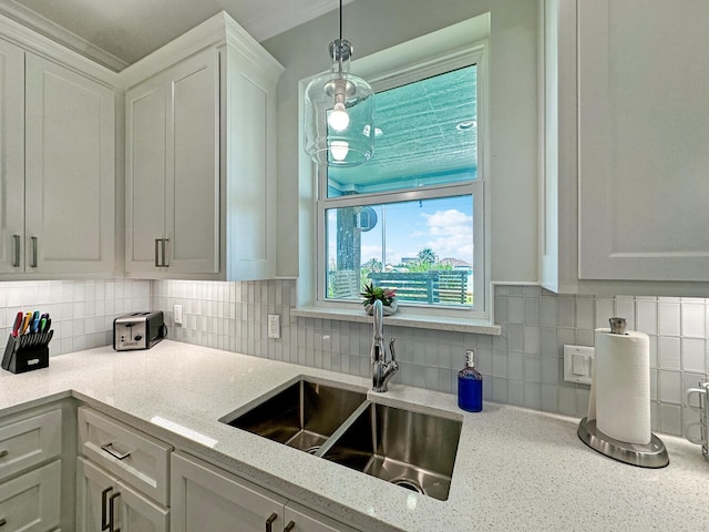 kitchen featuring decorative light fixtures, light stone countertops, sink, and white cabinets