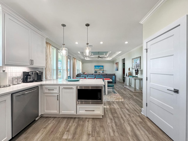 kitchen featuring white cabinetry, crown molding, stainless steel appliances, and light hardwood / wood-style floors