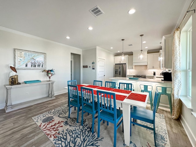 dining room with ornamental molding and light hardwood / wood-style floors