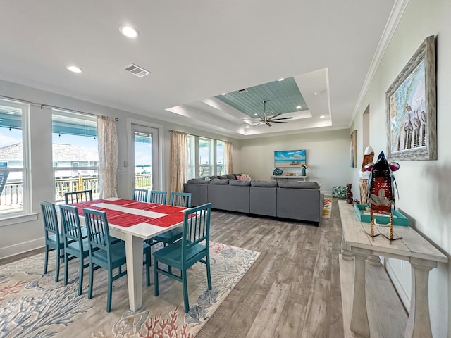 dining area with ornamental molding, light hardwood / wood-style flooring, ceiling fan, and a tray ceiling