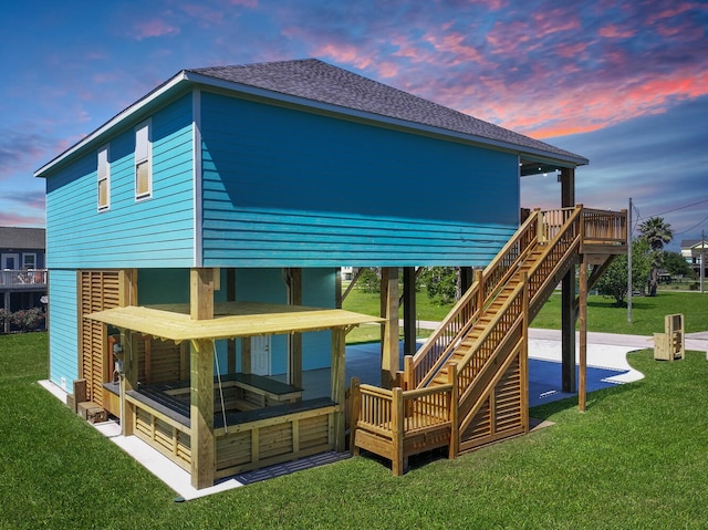 back house at dusk with a lawn and a deck