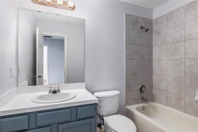 full bathroom featuring tiled shower / bath, vanity, and toilet