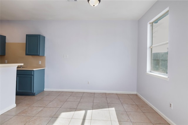 interior space with light tile patterned floors and blue cabinets