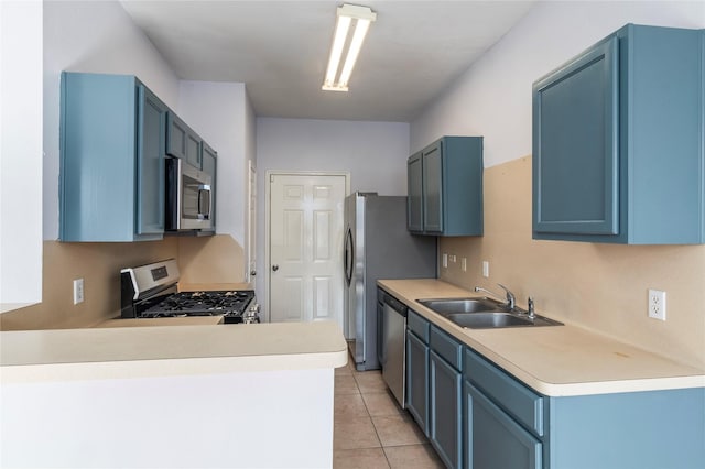 kitchen featuring appliances with stainless steel finishes, sink, light tile patterned floors, kitchen peninsula, and blue cabinetry