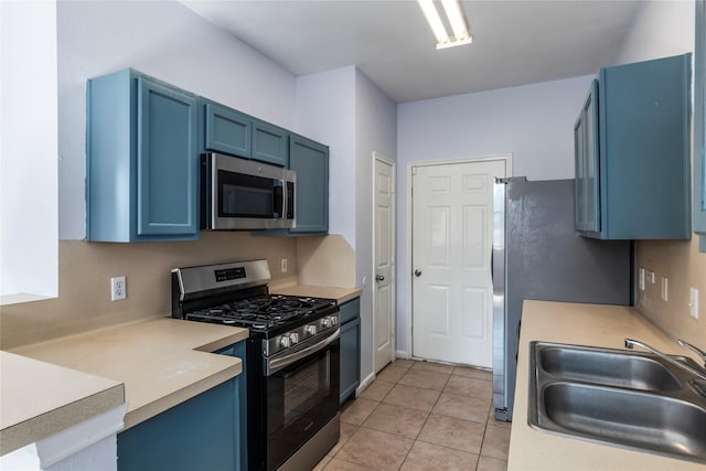 kitchen featuring blue cabinets, sink, light tile patterned floors, and appliances with stainless steel finishes