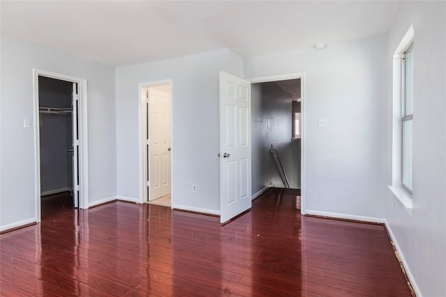 unfurnished bedroom with dark hardwood / wood-style floors and a spacious closet