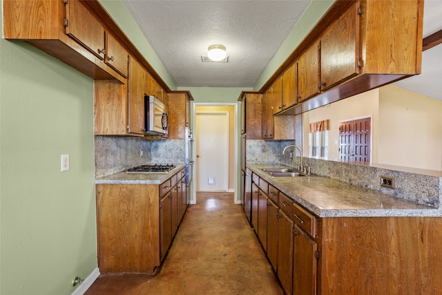 kitchen with tasteful backsplash, sink, stainless steel appliances, and a textured ceiling