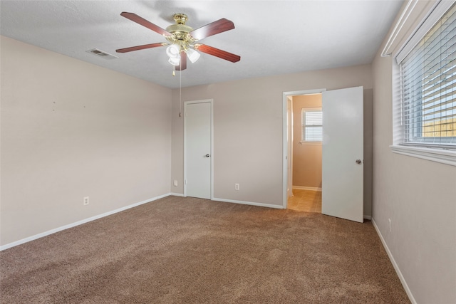 unfurnished bedroom with multiple windows, carpet floors, and ceiling fan