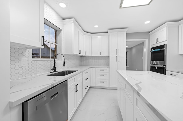 kitchen featuring sink, backsplash, stainless steel appliances, light stone countertops, and white cabinets