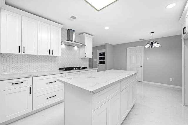 kitchen with wall chimney range hood, gas cooktop, white cabinetry, hanging light fixtures, and decorative backsplash