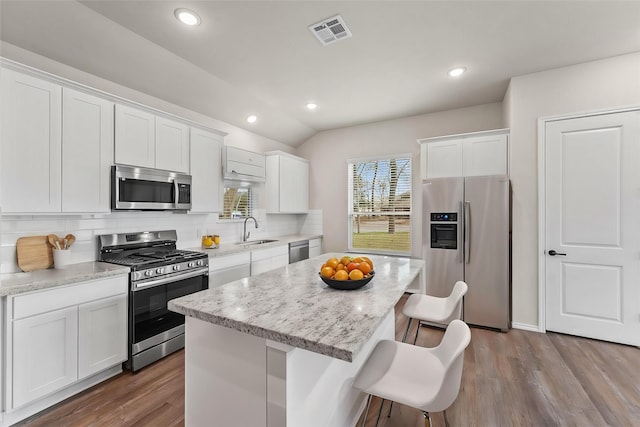 kitchen featuring sink, a breakfast bar area, a center island, appliances with stainless steel finishes, and white cabinets