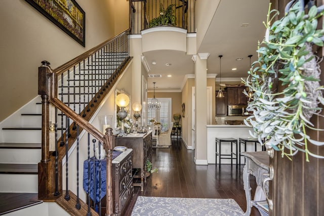 entryway with decorative columns, crown molding, dark hardwood / wood-style floors, and a towering ceiling