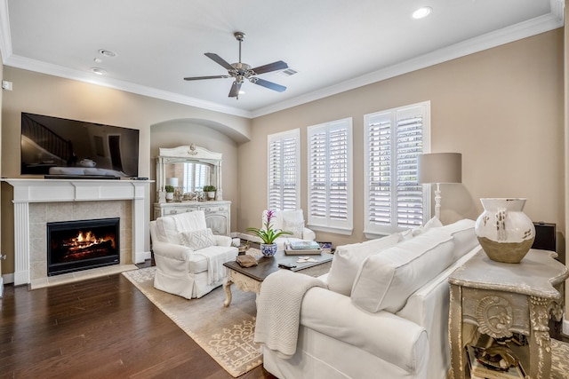 living room with a tiled fireplace, crown molding, and dark hardwood / wood-style floors