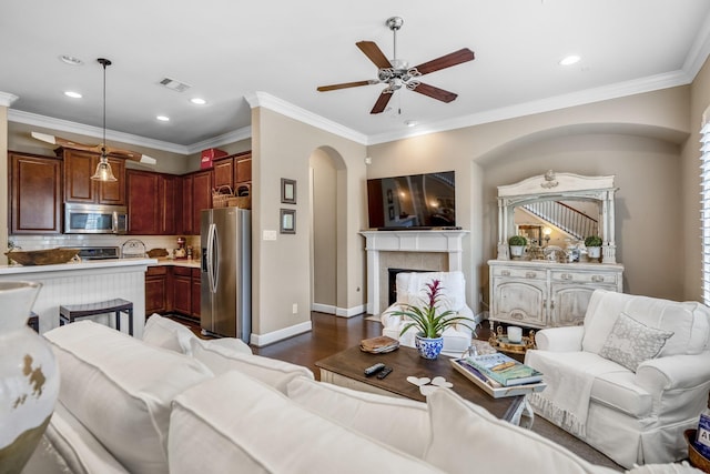 living room featuring dark wood-type flooring, a fireplace, and crown molding