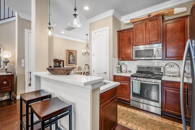 kitchen featuring hanging light fixtures, appliances with stainless steel finishes, a kitchen breakfast bar, and decorative backsplash