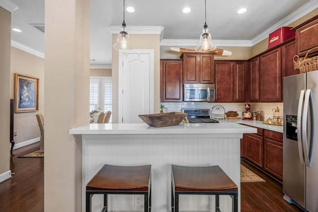 kitchen with ornamental molding, stainless steel appliances, decorative light fixtures, and a breakfast bar area