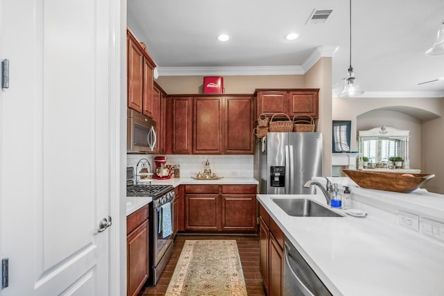 kitchen featuring pendant lighting, appliances with stainless steel finishes, crown molding, and sink