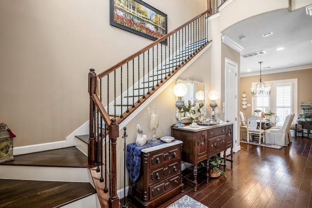 stairway with hardwood / wood-style flooring, ornamental molding, and a chandelier